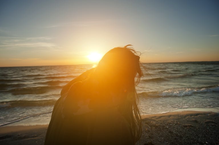 Silhouette of Woman Sitting on Beach Shore